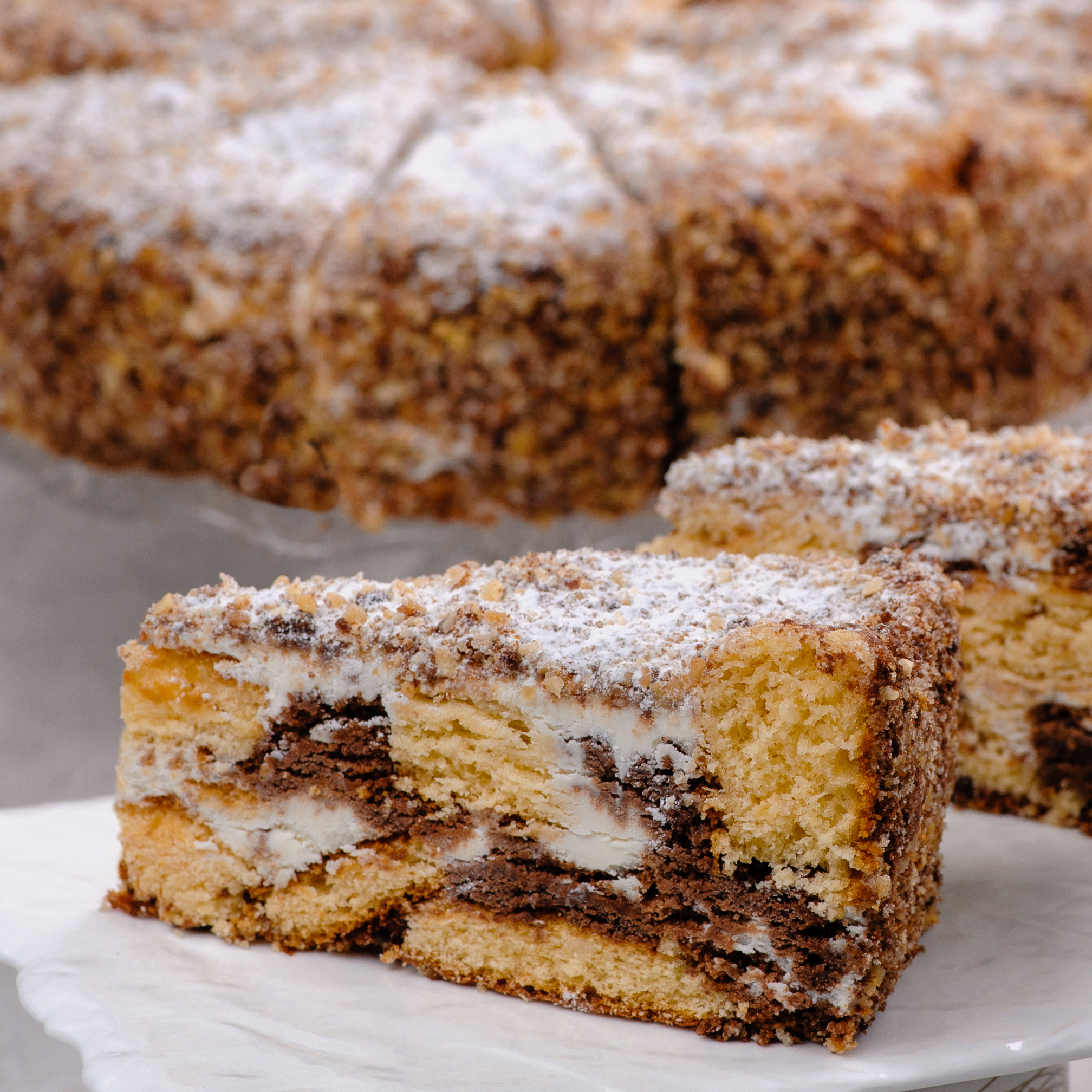 Белый и шоколадный бисквиты, прослоенные сметанным кремом. Торт украшен дроблёным орехом. изображение 1