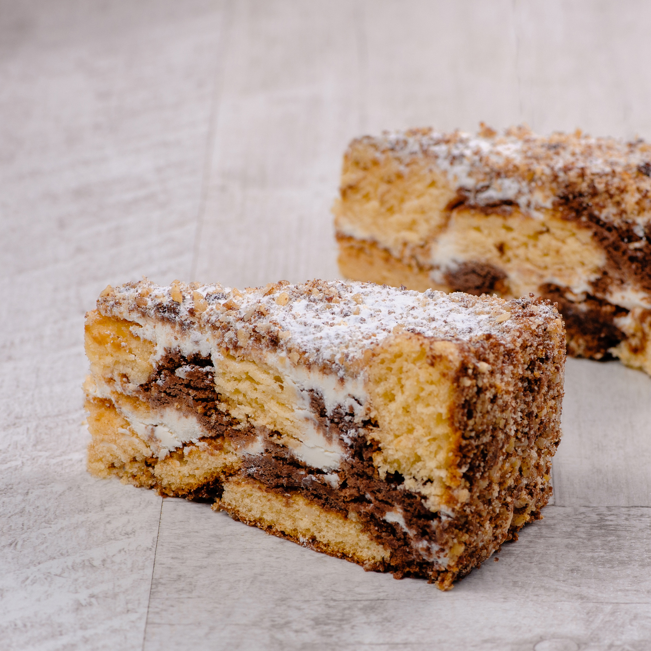 Белый и шоколадный бисквиты, прослоенные сметанным кремом. Торт украшен дроблёным орехом. изображение 2