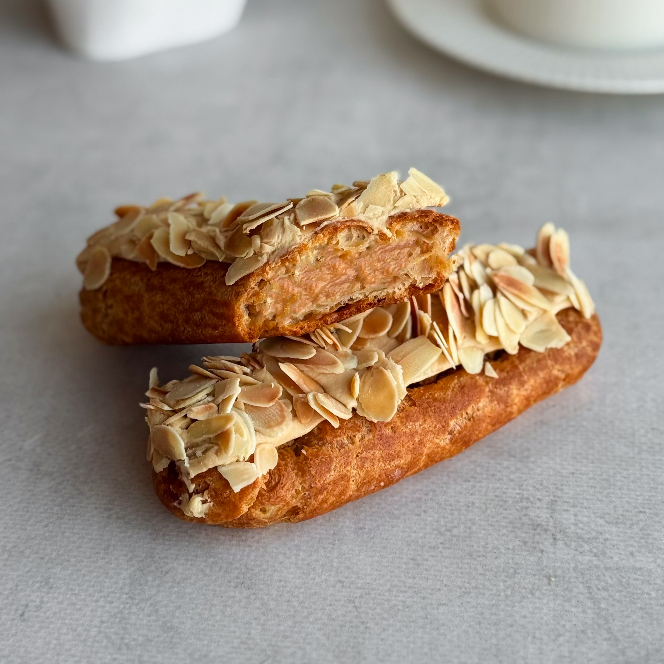 Карамельный эклер с кремом из взбитых сливок с карамелью, украшенный лепестками миндаля изображение 1