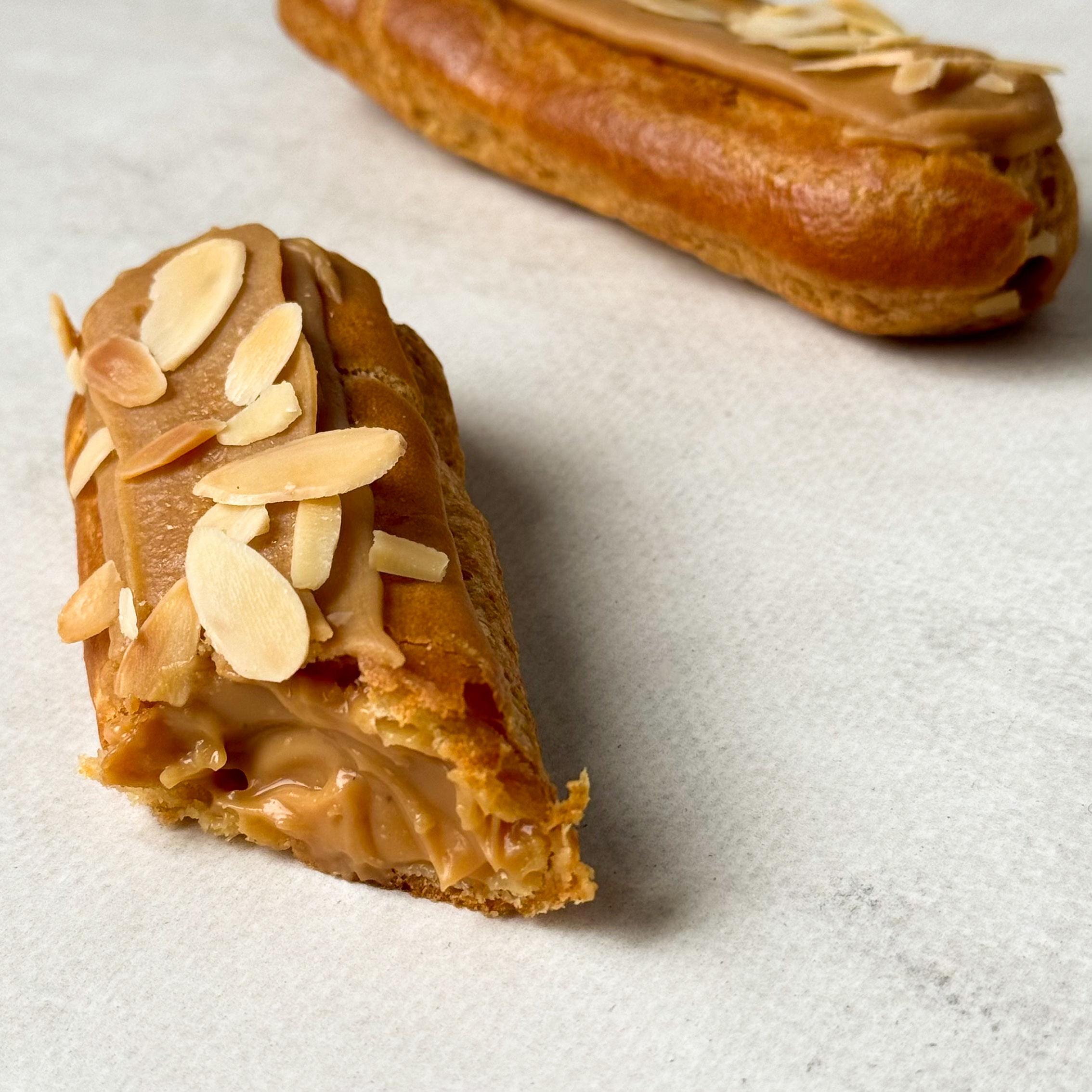 Карамельный эклер с кремом из взбитых сливок с карамелью, украшенный лепестками миндаля изображение 7