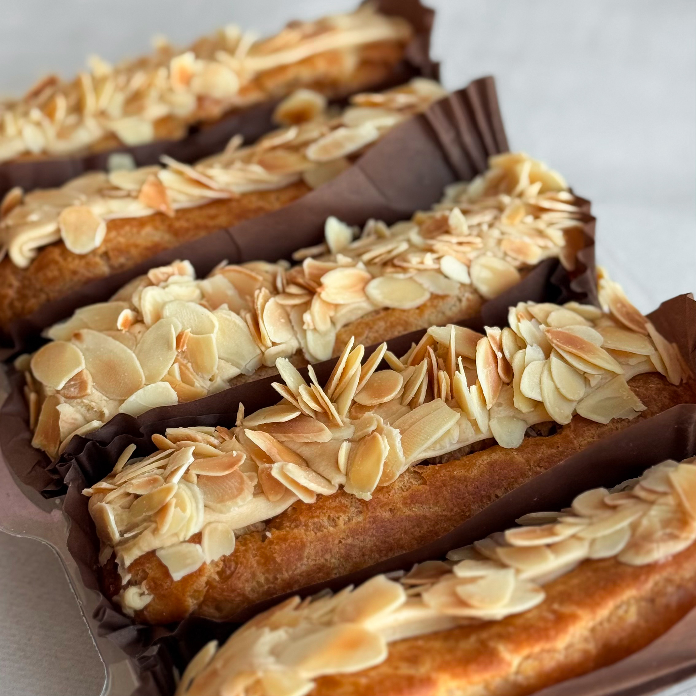 Карамельный эклер с кремом из взбитых сливок с карамелью, украшенный лепестками миндаля изображение 7