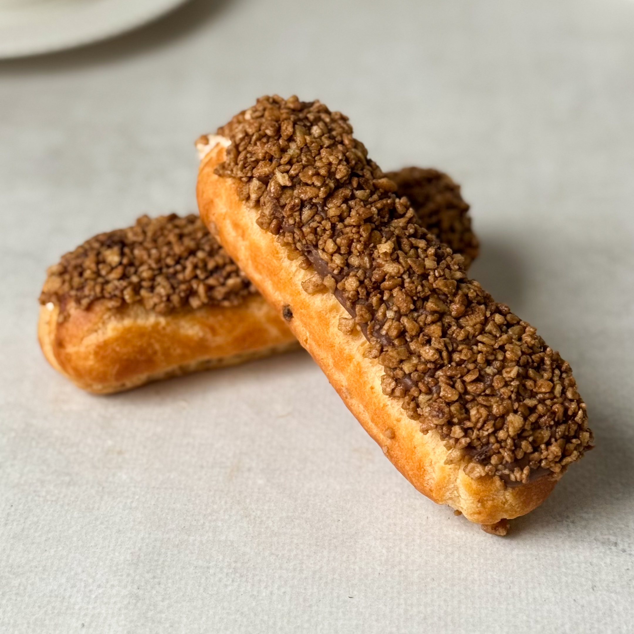 Ванильный эклер с начинкой из сливочного крема, покрытый шоколадной помадкой с посыпкой изображение 4