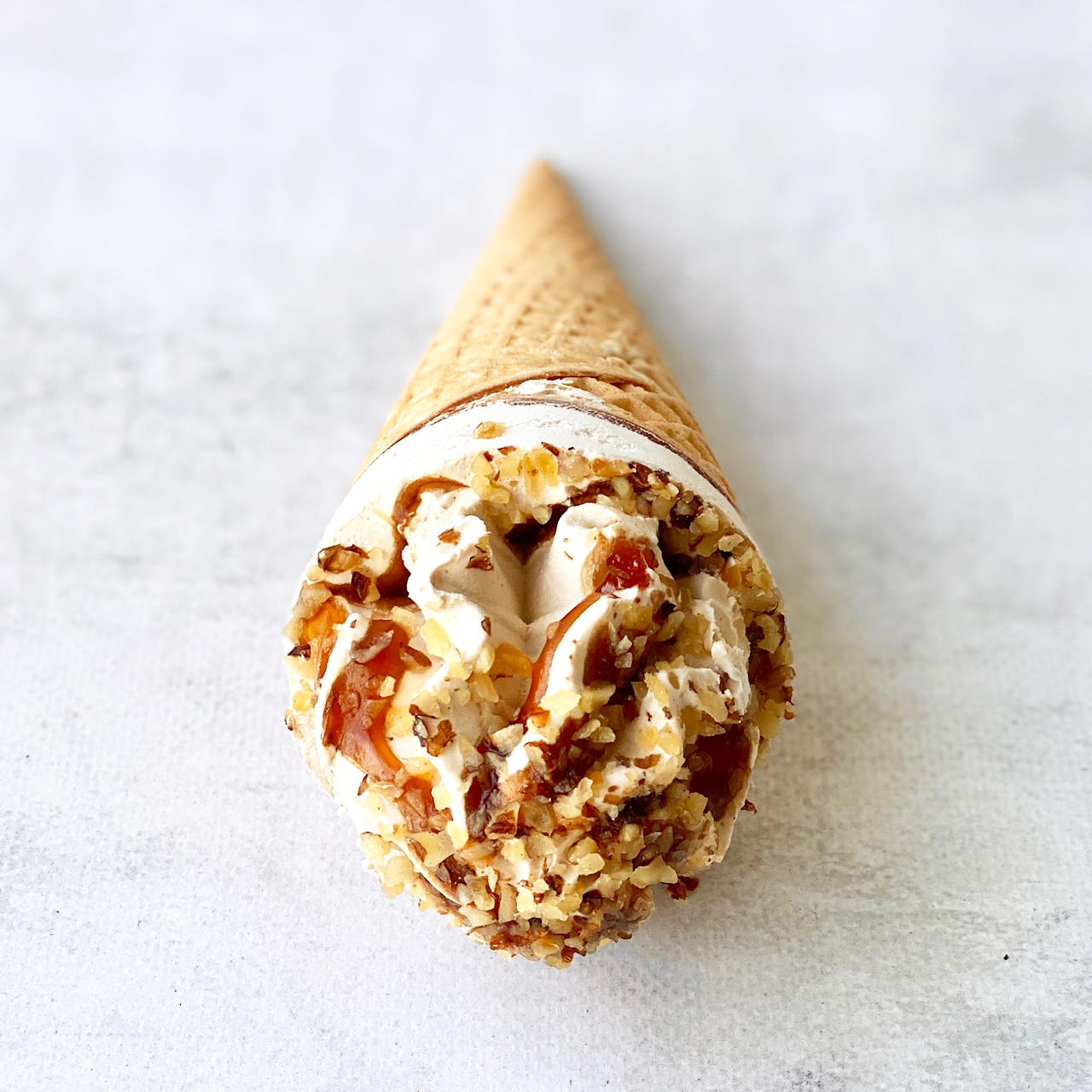 Мороженое сливочное с ароматом грецкого ореха, декорированное кленовым сиропом и грецким орехом в сахарном вафельном рожке с шоколадной глазурью изображение 3