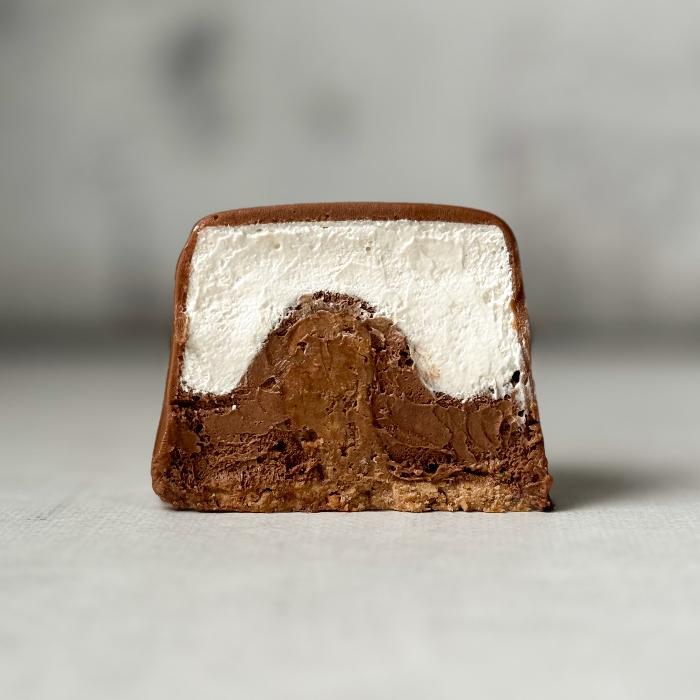 Два слоя из белого и темного шоколада с хрустящей сердцевиной из фундучного пралине, покрыто темным шоколадом. изображение 2