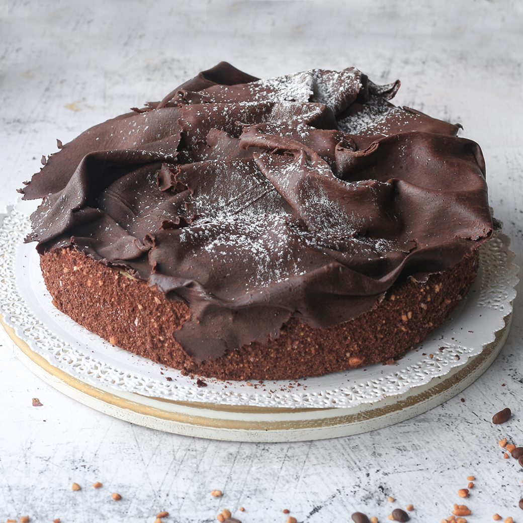 Шоколадный бисквит с заварным шоколадно-ореховым кремом украшенный темным шоколадом. Торт не нарезан. изображение 1