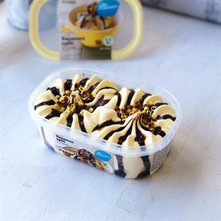 Сливочное банановое мороженое с шоколадным соусом и молочным шоколадом. Сверху украшено шоколадно-банановой стружкой