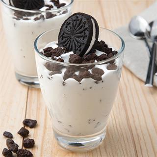 Мороженое в стеклянной креманке с печеньем с какао и начинкой с ванильным вкусом.