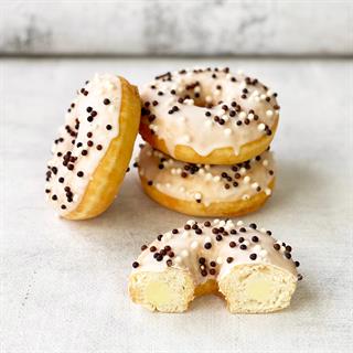 Пончик-донатс с ванильной начинкой, белой кондитерской глазурью с шоколадными шариками 