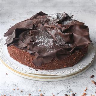 Шоколадный бисквит с заварным шоколадно-ореховым кремом украшенный темным шоколадом. Торт не нарезан.